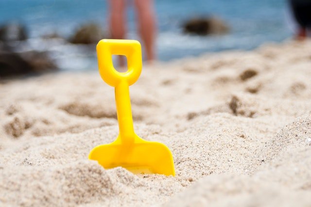 žlutá lopatka zapíchnutá v písku